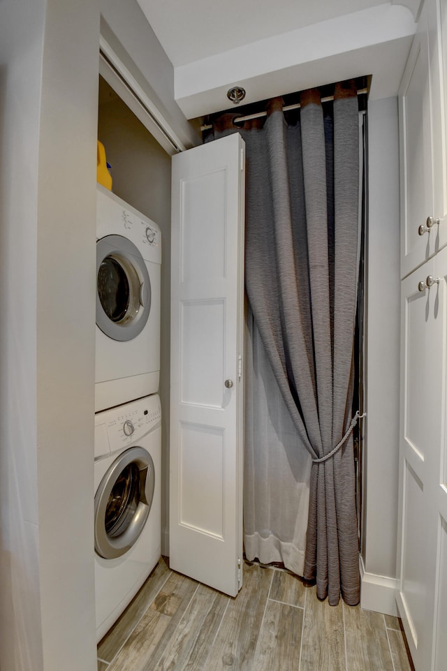 clothes washing area featuring light hardwood / wood-style floors and stacked washer / drying machine