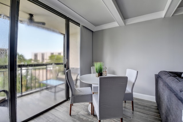 dining area featuring beamed ceiling, plenty of natural light, and hardwood / wood-style floors