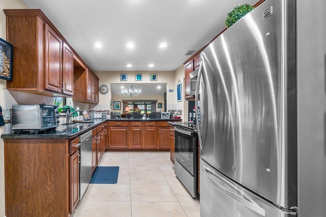 kitchen with sink, appliances with stainless steel finishes, dark stone countertops, and light tile floors