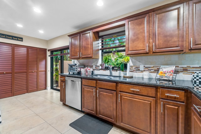 kitchen with backsplash, dishwasher, dark stone countertops, sink, and light tile floors