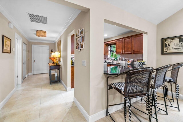 kitchen featuring kitchen peninsula, crown molding, and light tile flooring