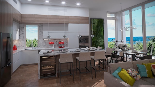 kitchen featuring black fridge, beverage cooler, white cabinetry, a water view, and a kitchen island