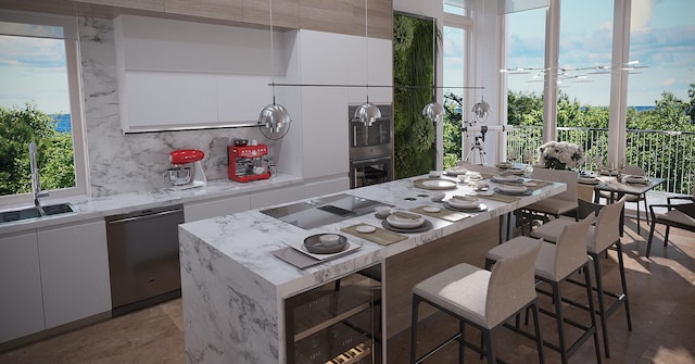 kitchen with backsplash, a kitchen island, appliances with stainless steel finishes, white cabinets, and sink