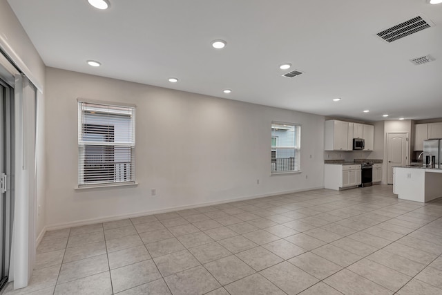 unfurnished living room featuring sink and light tile floors