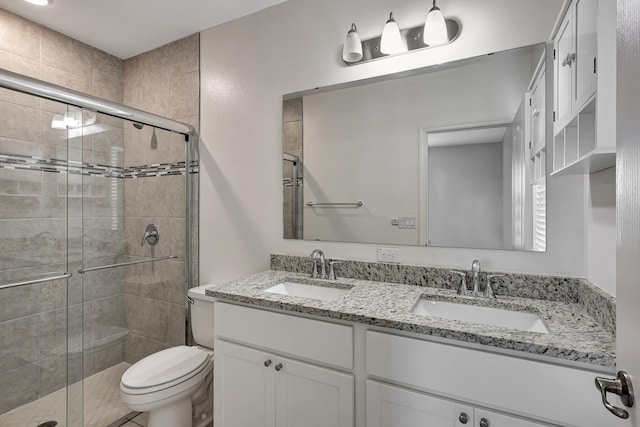 bathroom with an enclosed shower, toilet, and dual bowl vanity