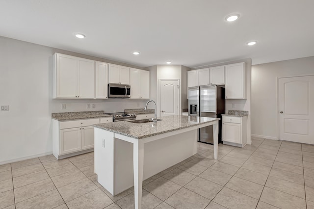 kitchen featuring stainless steel appliances, a kitchen island with sink, light stone counters, sink, and light tile floors