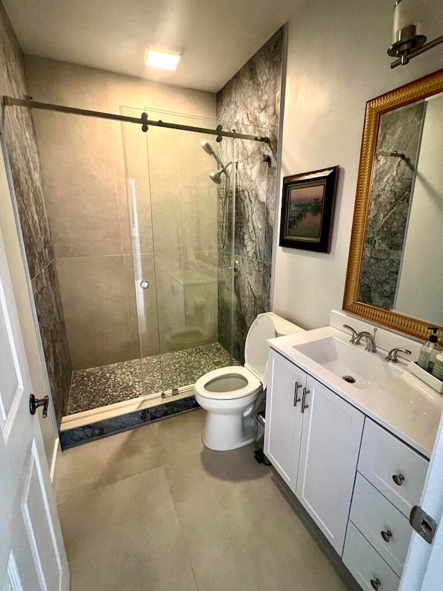 bathroom with a shower with door, vanity, and toilet