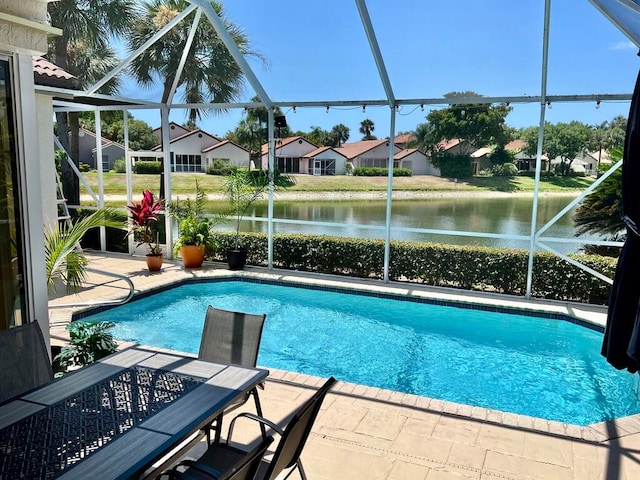 view of pool with a patio, glass enclosure, and a water view