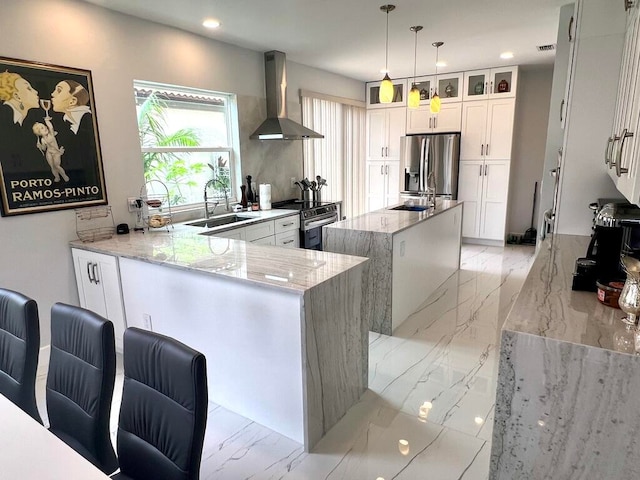 kitchen featuring light stone countertops, white cabinets, stainless steel fridge, wall chimney exhaust hood, and kitchen peninsula