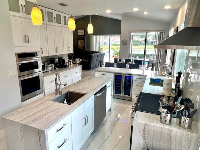 kitchen with white cabinets, vaulted ceiling, light stone counters, and sink