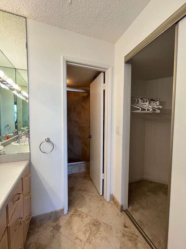 bathroom with tile flooring, vanity, and a textured ceiling