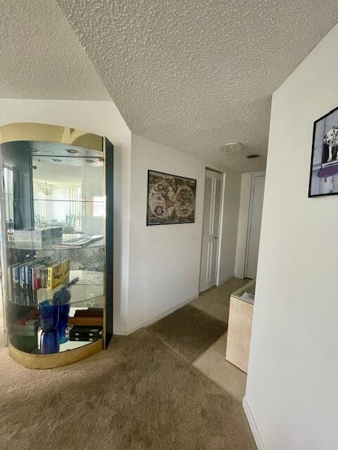 hallway with a textured ceiling and carpet flooring