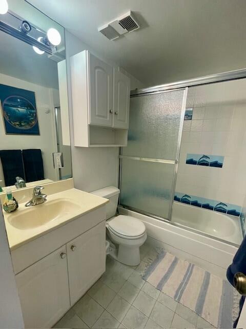 full bathroom with bath / shower combo with glass door, vanity, toilet, and tile floors