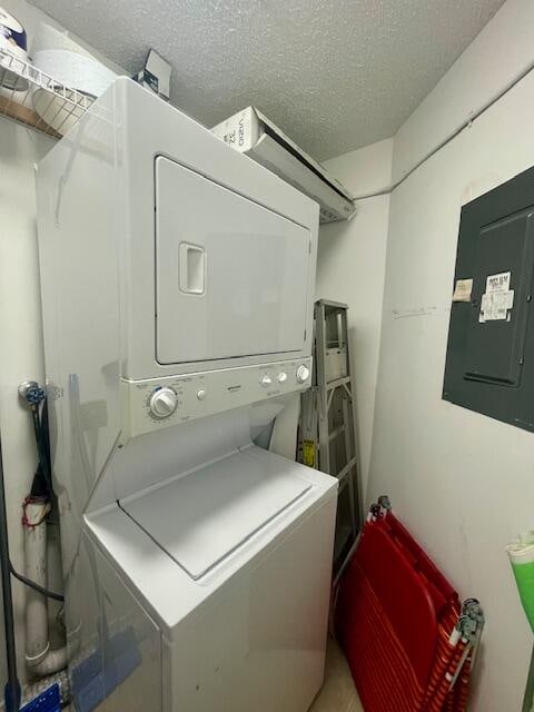 clothes washing area featuring a textured ceiling and stacked washer / drying machine