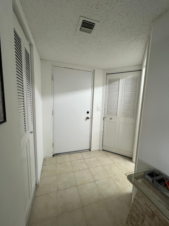 corridor with light tile flooring and a textured ceiling