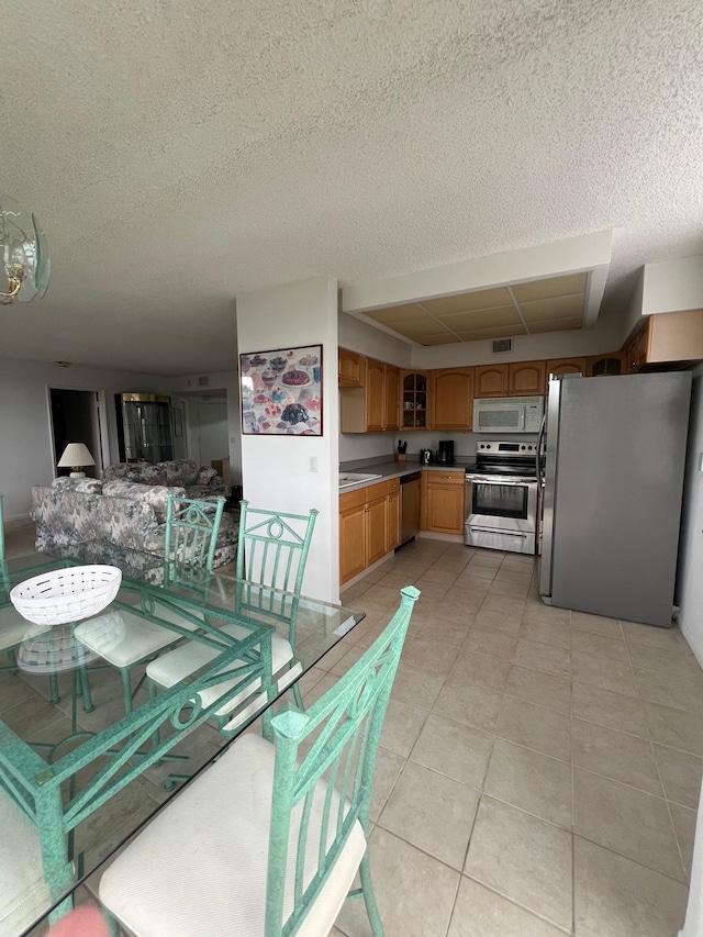 dining room with sink, a textured ceiling, and light tile floors