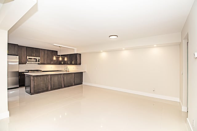 kitchen featuring dark brown cabinets, stainless steel appliances, kitchen peninsula, and tasteful backsplash