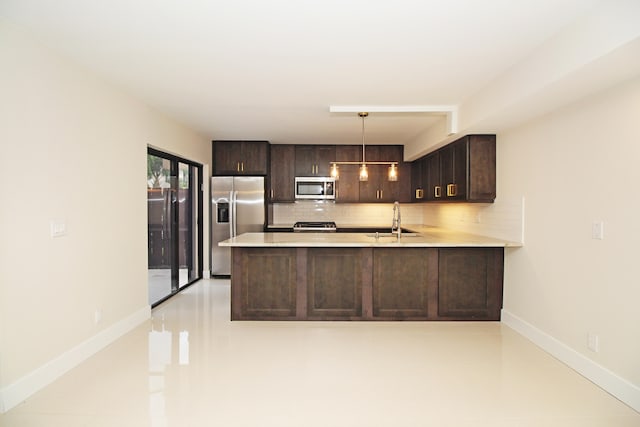 kitchen featuring stainless steel appliances, backsplash, dark brown cabinets, sink, and pendant lighting