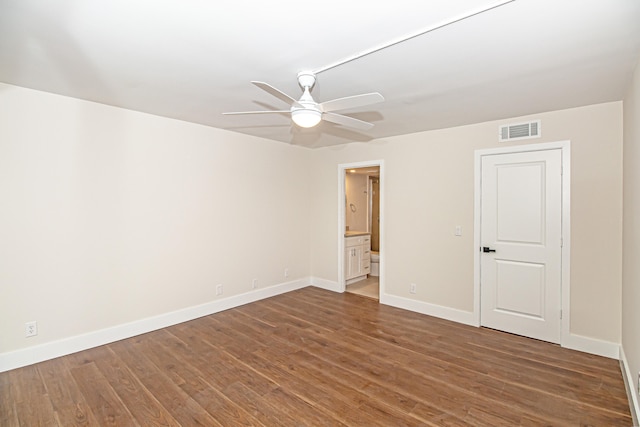 unfurnished bedroom featuring dark hardwood / wood-style floors, ceiling fan, and connected bathroom