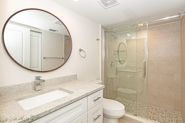 bathroom featuring a shower with door, vanity, and toilet