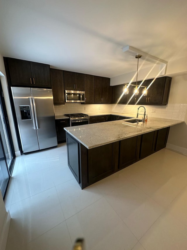 kitchen featuring appliances with stainless steel finishes, kitchen peninsula, backsplash, pendant lighting, and sink