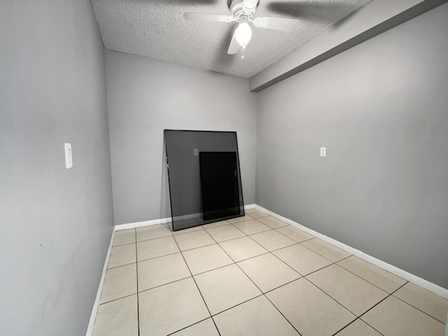 tiled empty room with ceiling fan and a textured ceiling