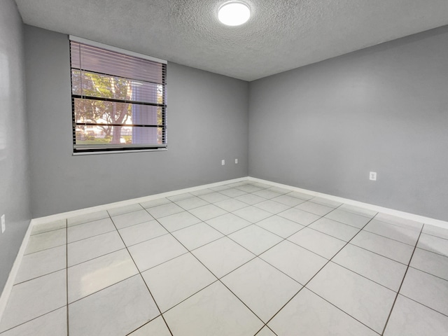 unfurnished room featuring a textured ceiling and light tile flooring