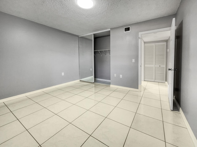 unfurnished bedroom with a closet, light tile floors, and a textured ceiling