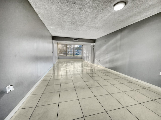 tiled empty room featuring a textured ceiling