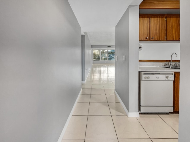 kitchen with sink, white dishwasher, and light tile flooring