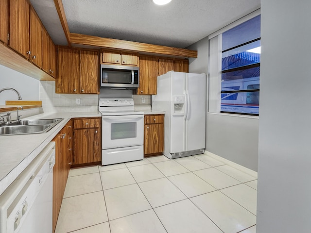 kitchen with a textured ceiling, sink, white appliances, light tile flooring, and tasteful backsplash