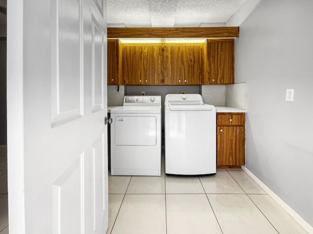 washroom featuring washer and clothes dryer, cabinets, light tile floors, and a textured ceiling