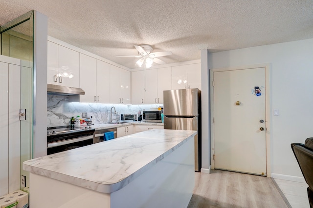 kitchen with a center island, white cabinetry, appliances with stainless steel finishes, light hardwood / wood-style floors, and ceiling fan