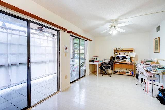 home office with a textured ceiling, light wood-type flooring, and ceiling fan