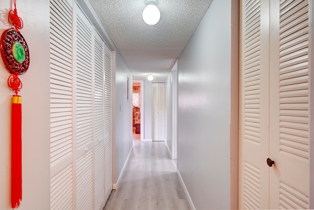 hallway featuring light hardwood / wood-style floors and a textured ceiling