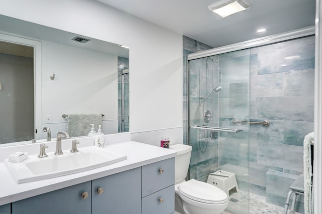 bathroom with vanity, toilet, and a shower with door