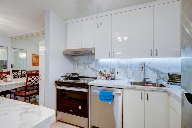 kitchen featuring appliances with stainless steel finishes, sink, a textured ceiling, white cabinetry, and decorative backsplash