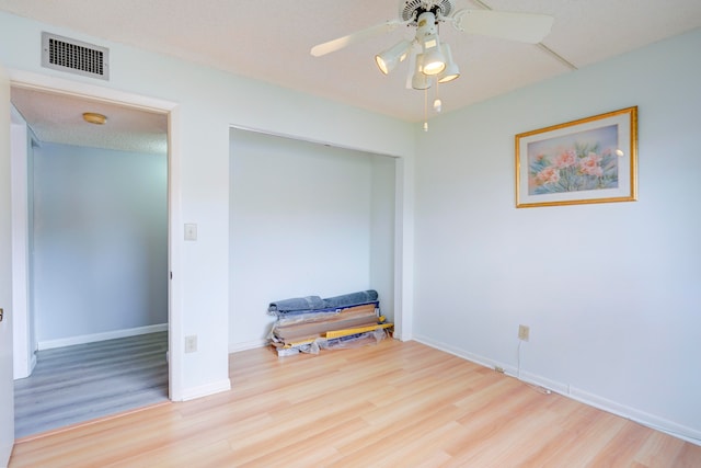 bedroom with ceiling fan, a textured ceiling, and light hardwood / wood-style floors