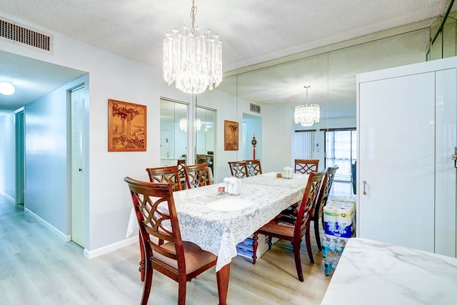 dining room featuring a textured ceiling, a chandelier, and light wood-type flooring