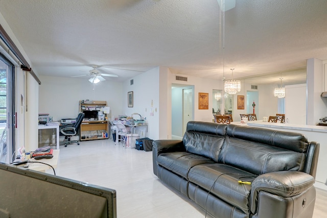 living room featuring a textured ceiling and ceiling fan with notable chandelier