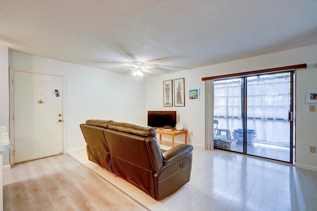 living room with light hardwood / wood-style floors, a textured ceiling, and ceiling fan