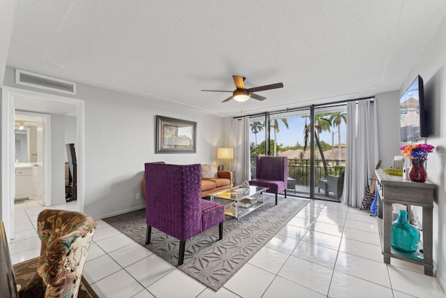 living room with a wealth of natural light, ceiling fan, light tile patterned flooring, and a textured ceiling