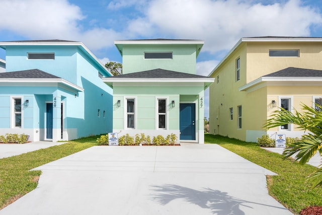 view of front of house featuring a front yard, roof with shingles, and stucco siding