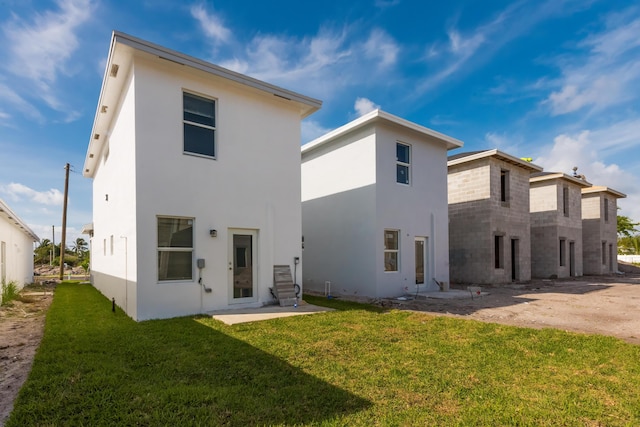 rear view of property with a yard, a patio area, and stucco siding