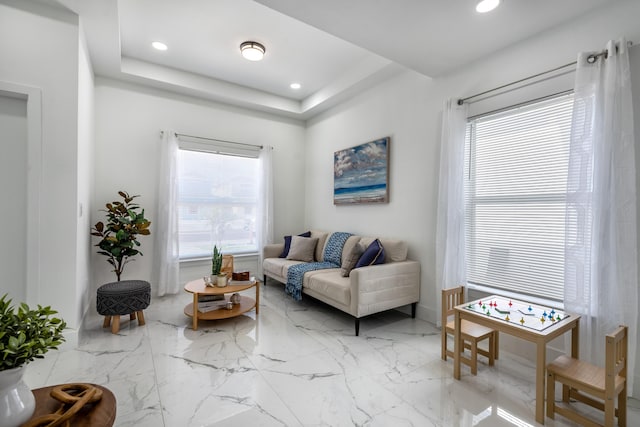 living room with recessed lighting, marble finish floor, and a tray ceiling