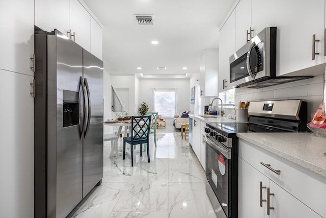 kitchen featuring visible vents, marble finish floor, a sink, tasteful backsplash, and appliances with stainless steel finishes