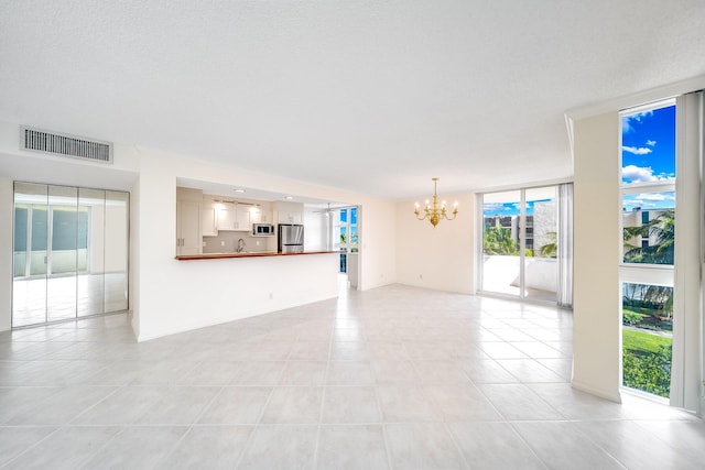 unfurnished living room with a notable chandelier, ornamental molding, light tile patterned flooring, and floor to ceiling windows