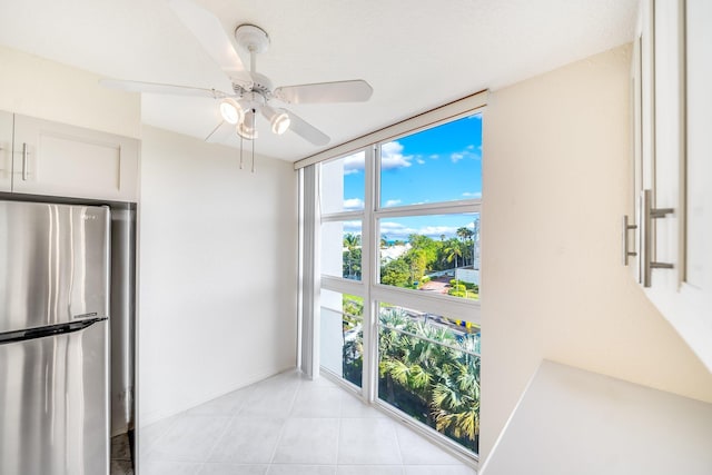 kitchen featuring white cabinets, ceiling fan, expansive windows, and stainless steel fridge