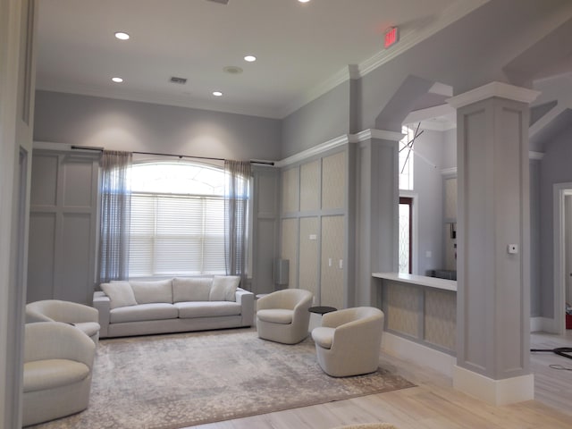 living room with ornamental molding, a chandelier, and light hardwood / wood-style flooring