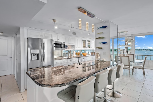 kitchen featuring light tile floors, hanging light fixtures, a breakfast bar area, white cabinetry, and appliances with stainless steel finishes